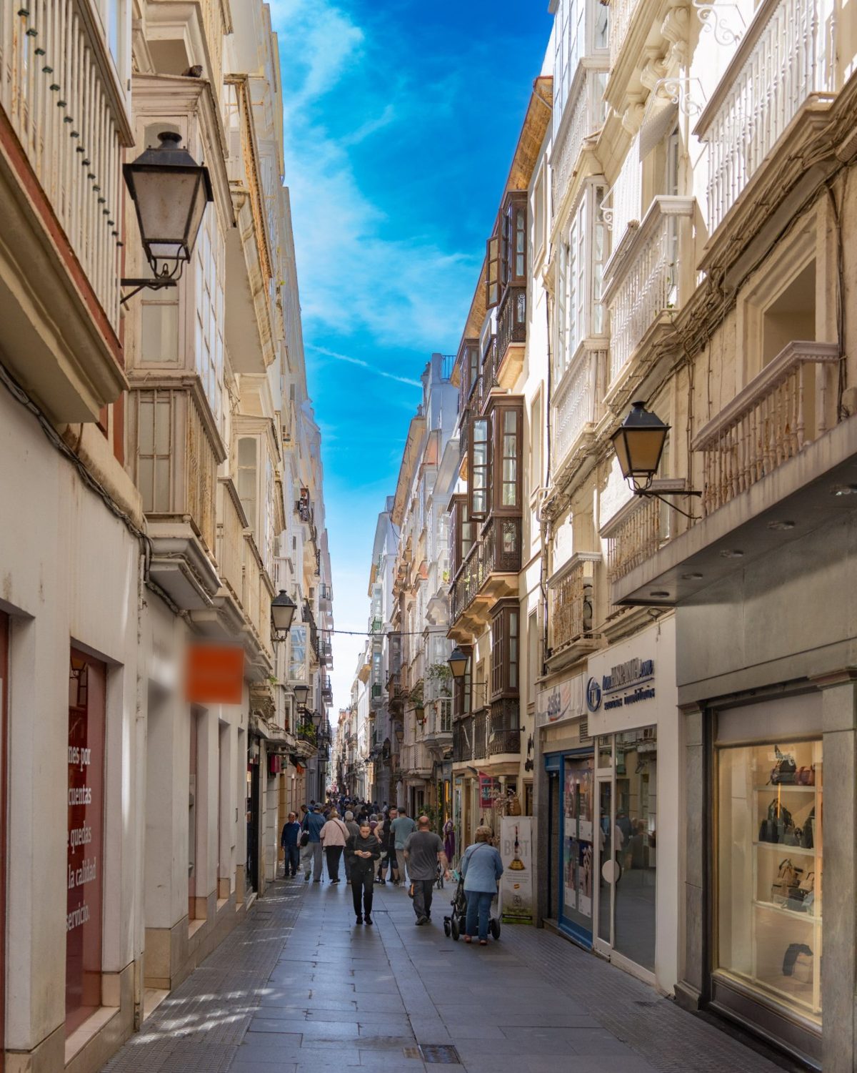 Calle comercial peatonal con pequeños comercios y gente paseando